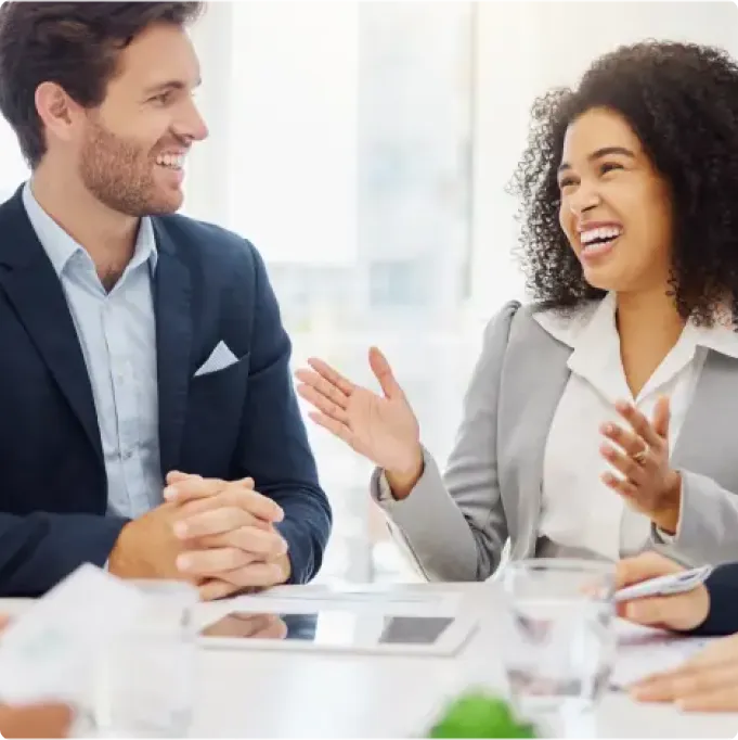 A man and a woman are sitting at a table, smiling and engaging in conversation